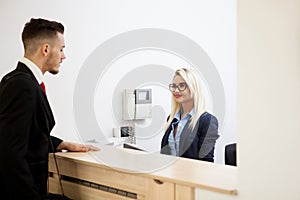 Businessman in office reception area talking with secretary