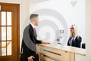 Businessman in office reception area talking with secretary