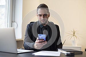businessman in office sending messages with mobile phone smiling