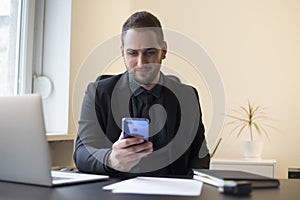 businessman in office sending messages with mobile phone smiling