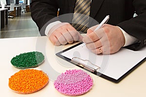Businessman in the office signs a contract for the supply of plastic granules for industry. Plastic raw material in granules