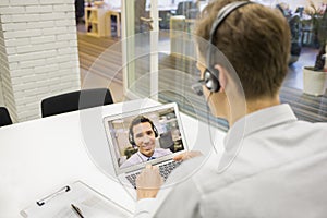 Businessman in the office on videoconference with headset, Skype photo