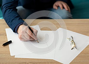 Businessman in the office writes a letter or signs a document on a piece of white paper with a fountain pen with nib.