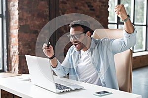 Businessman with open mouth sitting at the desk in front of a laptop