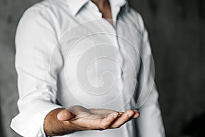 Businessman with open palm offering something. Close-up of young businessman`s hand in concept of holding or giving