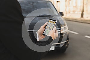 Businessman ordering taxi with smartphone on city street, closeup