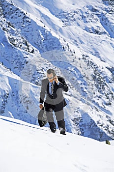 Businessman outdoors on snowy mountain using phone