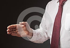 Businessman outsretched his hand for handshake over black background. Cropped man in white shirt and tie, close up