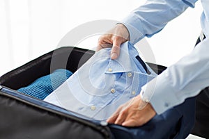 Businessman packing clothes into travel bag