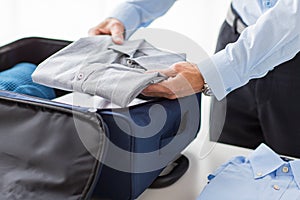 Businessman packing clothes into travel bag