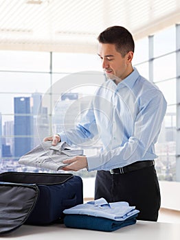 Businessman packing clothes into travel bag