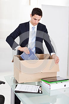 Businessman Packing Files In Cardboard Box In Office