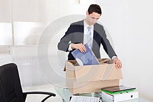 Businessman packing files in cardboard box in office