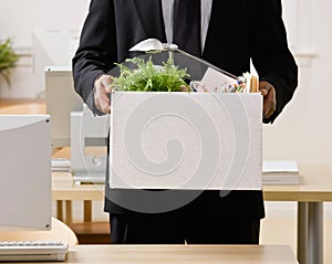 Businessman packing personal desk items in box