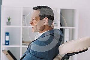 businessman with painful backache sitting in massage chair