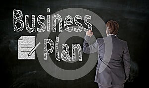 Businessman paints business plan on blackboard concept