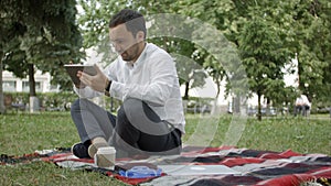 Businessman at the park with tablet. Young businessman at the park working with tablet