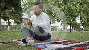 Businessman at the park with tablet. Young businessman at the park working with tablet