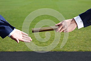 Businessman passing baton to his partner outdoors, closeup