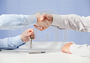 Businessman passing keys to his partner and shaking his hand