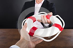 Businessman Passing A Lifebuoy To A Partner