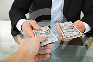 Businessman passing money to colleague at table