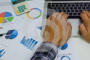 Businessman person hand using keyboard computer laptop with document chart finance and graph report investment at office.Paperwork