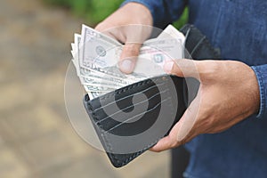 Businessman Person holding a wallet in the hands of an man take money out of pocket in the outdoor. Leave space to write messages.