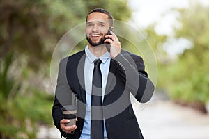 Businessman, phone and city park with coffee for happiness, conversation and worker break. Urban corporate employee