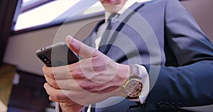 Businessman phone conversation. A young man stands in suit in the office near the window and puts the phone in his