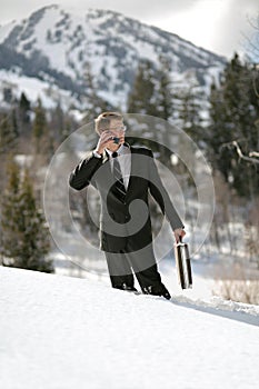 Businessman on phone walking in snowy wilderness
