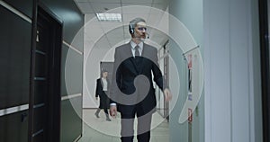 Businessman phoning with headset in office corridor