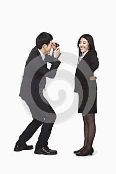 Businessman photographing businesswoman, studio shot