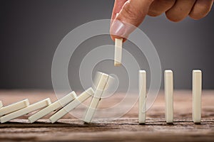 Businessman Picking Domino Piece On Wooden Table