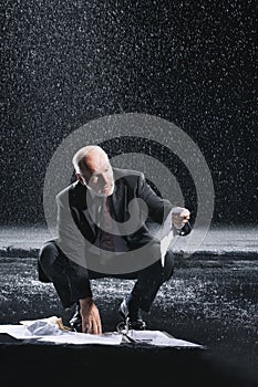 Businessman Picking Soaked Documents In Rain