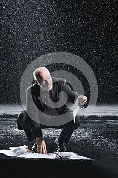 Businessman Picking Soaked Documents In Rain photo