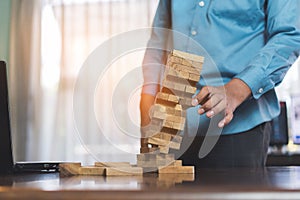 Businessman picking wooden block fail danger tower hands holding challenge game