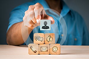 A businessman picks up a wood block with a symbol for an operator and icons for after-sales services. Customer satisfaction