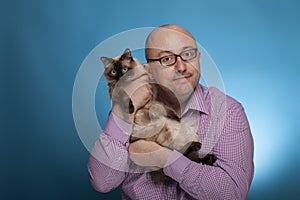 A businessman in a piked shirt holds a birman cat in the hand