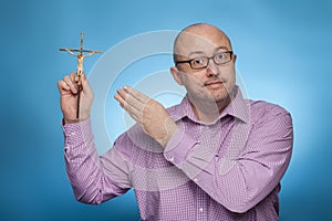 A businessman in a piked shirt pointing with the hand on a crucifix