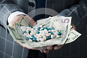 Businessman with a pile of pills and dollar bills