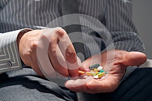 Businessman with a pill, hands close view - concept of difficulties, depression, problems, health and stress, risk of modern