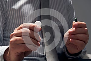 Businessman with a pill, hands close view - concept of difficulties, depression, problems, health and stress, risk of modern