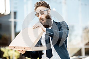 Businessman with pizza outdoors