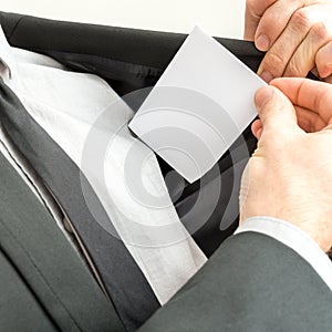 Businessman placing a blank business card in the inner pocket of