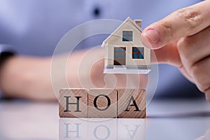 Businessman Placing House Models On HOA Cubic Blocks