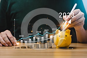 Businessman planning 2023 business growth on desk with virtual hologram chart graph.