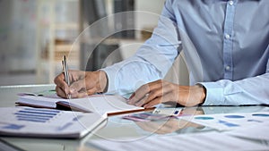 Businessman planning budget writing in notebook at office, small business income