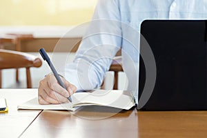 Businessman planning writing note and working with laptop computer on desk. Writing something idea on notebook or check list,