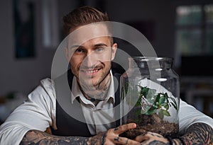 A businessman with plant terrarium sitting at the desk indoors in office.